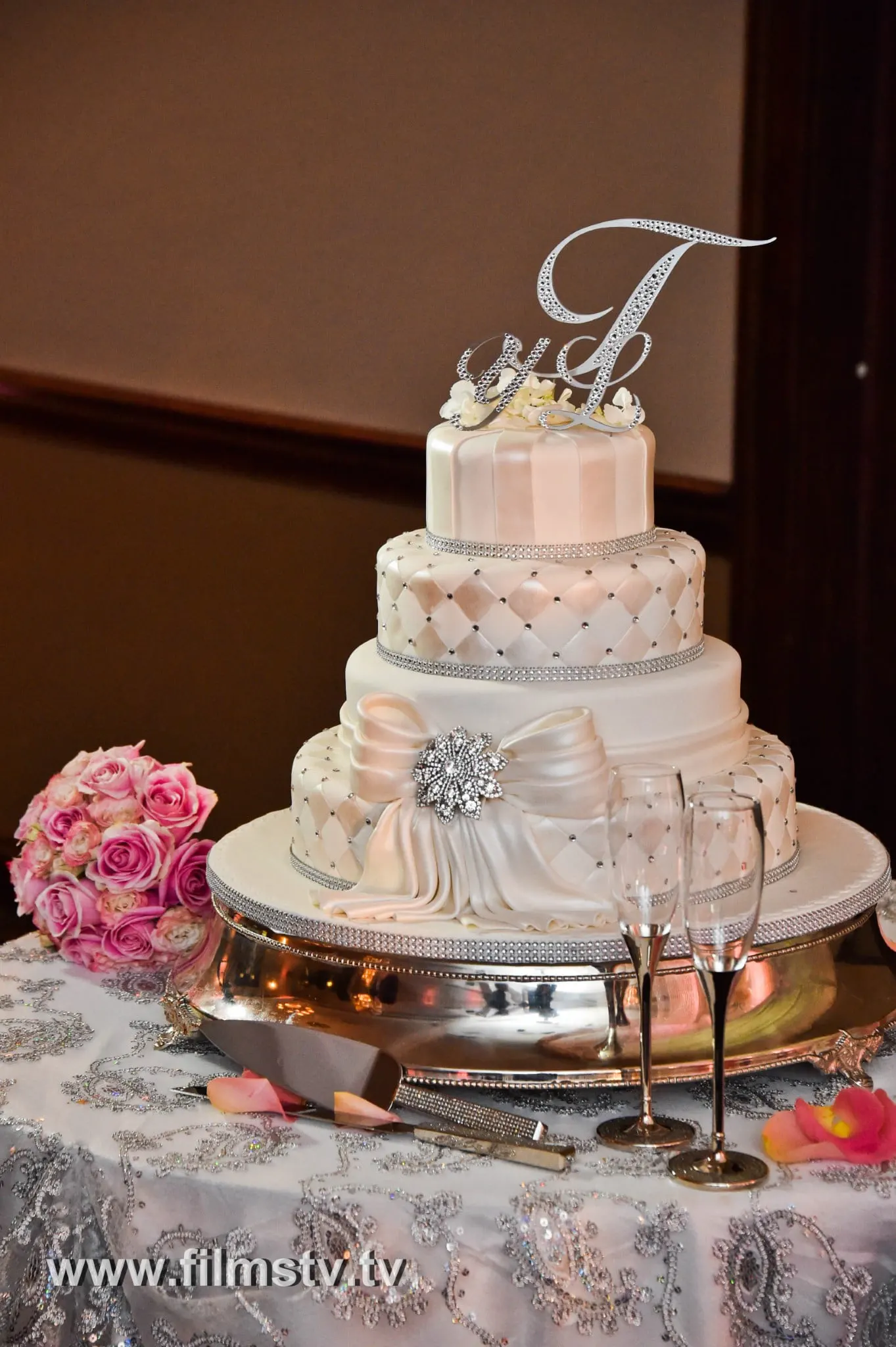 A white wedding cake with a monogram on top.