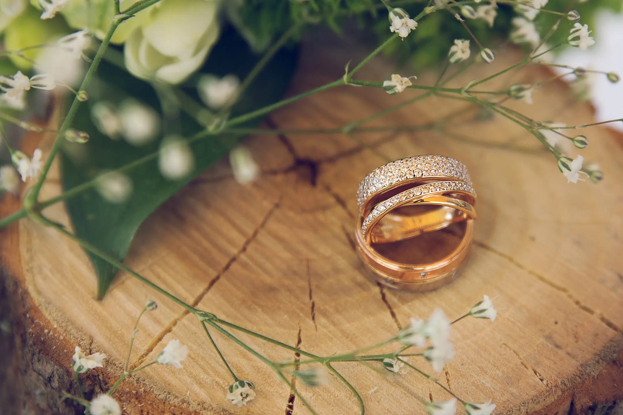 A wedding ring sits on top of a tree stump.
